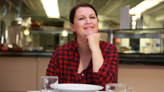 Maja Herzbach sitzt lächelnd an einem Tisch. © NDR Foto: Janis Röhlig