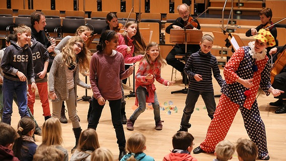 Kinder und Clown tanzen bei der Mit-Mach-Musik. © NDR Foto: Marcus Krüger