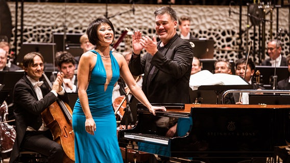Konzertszene: Yuja Wang (am Flügel) verbeugt sich, Alan Gilbert und die Musikerinnen und Musiker des NDR EO applaudieren der Pianistin © NDR Foto: Peter Hundert