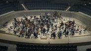 Musikerinnen und Musiker schauen auf die leeren Plätze der Bratschen im NDR Elbphilharmonie Orchester während einer Probe in der Elbphilharmonie. © NDR Foto: Screenshot