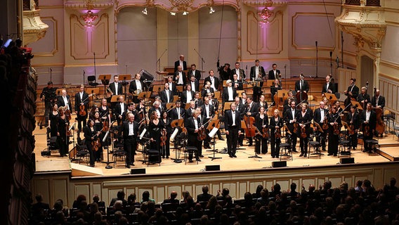 Applausszene: Thomas Hengelbrock und das NDR Sinfonieorchester stehen auf der Bühne der Laeiszhalle. © NDR Foto: Marcus Krueger