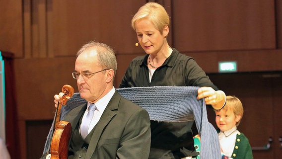 Moderatorin Susanne Grünig behängt einen Geiger mit einem Schal. © NDR Foto: Michael Plümer