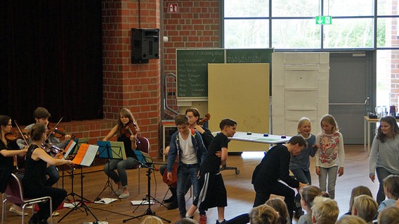 Szene aus einem Schulkonzert: Kinder und Musiker auf der Bühne.  Foto: Wito Gasthaus