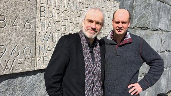 Uģis Prauliņš und Stephen Layton vor einer Steintafel.  Foto: Kristien Daled
