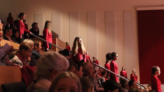 Junge Sängerinnen stehen zwischen Zuschauerrängen. © NDR Foto: Thomas Becker