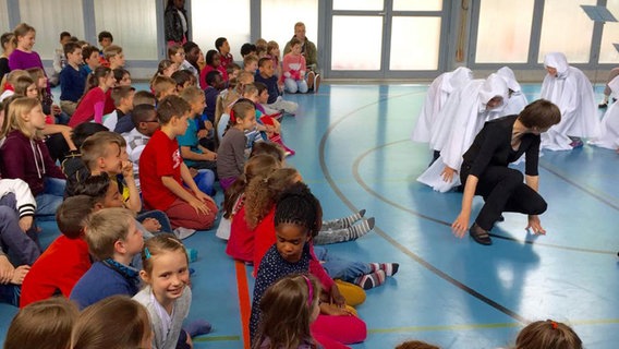 Musikalischer Besuch in der Schule: verkleidete Kinder in einer Turnhalle. © NDR Foto: K. Daled