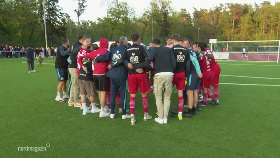 Das Team des Greifswalder FC steht auf dem Fußballfeld geschlossen im Kreis. © Screenshot 