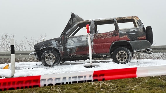 Ein ausgebrannter Geländewagen steht in Mitten von weißem Löschschaum. © NDR Foto: Felix Gadewolz