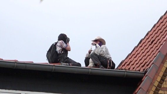 Zwei Menschen sitzen auf dem Dach eines besetzen Hauses in Hannover. © TeleNewsNetwork 
