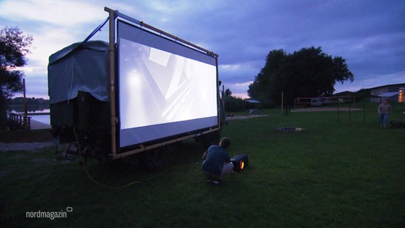 Ein Film wird unter freiem Himmel auf einer Leinwand gezeigt, die an einem LKW befestigt ist. © Screenshot 