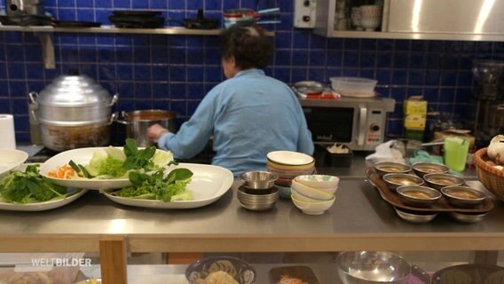 Blick in eine Restaurant-Küche. Auf einer Anrichte stehen Teller, Schüsseln und Schalen bereit. © Screenshot 
