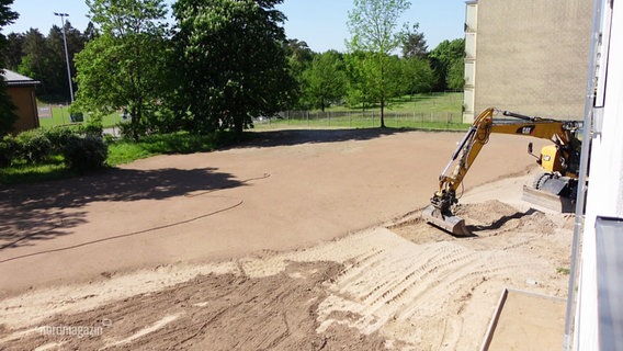 Ein Bagger schaufelt Sand auf einer Baustelle. © Screenshot 