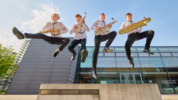 Vier junge Männer springen mir ihren Instrumenten in die Luft. © Oliver Borchert 