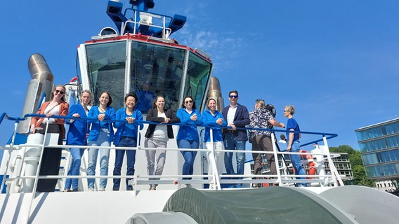 Frauen in Berufen der Schiffahrt stehen gemeinsam mit Wirtschaftssenatorin Melanie Leonhard auf einem Schiff. © Dietrich Lehmann 