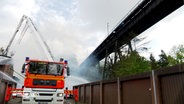 Eine Drehleiter der Feuerwehr ist auf ihren Stützen aufgebockt, Feuerwehrleute löschen ein Feuer neben der Eisenbahnhochbrücke in Rendsburg © NDR Foto: NDR Screenshot