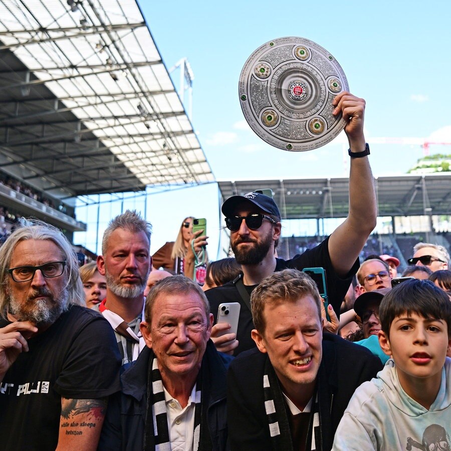 Ein Fan des FC St. Pauli hält beim Bundesliga-Aufstieg eine Meisterschale in die Höhe. © Witters/LeonieHorky 