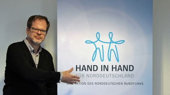 Der Hamburger Landesleiter der Caritas, Michael Edele, neben einem Aufsteller mit der Aufschrift "Hand in Hand für Norddeutschland".  Foto: Alexander Heinz