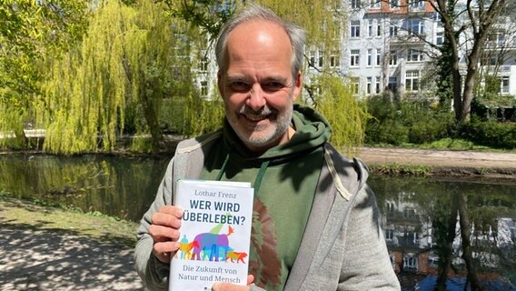 Der Hamburger Biologe Lothar Frenz hält ein Buch in die Kamera. © NDR 