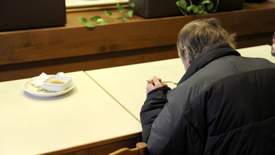 Ein Obdachloser sitzt an einem Tisch und isst. © picture alliance / dpa Foto: Tobias Hase