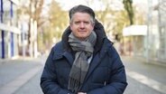 Ein Mann mit Schal und Daunenjacke steht auf der Straße © NDR 90,3 Foto: Lisanne Drägert