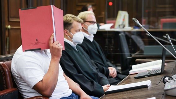 Der Angeklagte (l.) sitzt zu Beginn des Prozesses neben seinen Anwälten Dennis Dördrechter (M.) und Christian Denzel im Gerichtssaal im Strafjustizgebäude. Der 23-Jährige muss sich wegen Totschlags vor dem Landgericht Hamburg verantworten. © picture alliance/dpa Foto: Christian Charisius