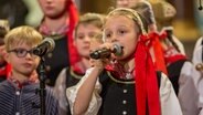 Ein Mädchen in traditioneller Tracht singt für die Lütt Finkwarder Speeldeel beim Weihnachtshafenkonzert im Hamburger Michel. © NDR Foto: Axel Herzig