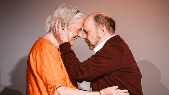 Eine ältere Frau mit grauem Haar und ein älterer Mann umarmen sich Stirn an Stirn © Kleines Hoftheater Foto: Markus Richter