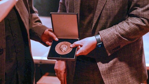 Zwei Hände halte eine Schatulle mit der Biermann Ratjen Medaille für den Hamburger Autor Frank Göhre © NDR Foto: Screenshot Hamburg Journal
