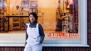 Quartierskünstlerin Ji Hyung Nam steht vor dem Schaufenster ihres Ateliers in der Straßburger Straße in Dulsberg © Mike Schäfer Foto: Mike Schäfer