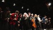 Auf der Bühne verbeugt sich eine Reihe von Musikern und Musikerinnen mit weißen Rosen in der Hand. In der Mitte die Pianistin Martha Argerich. © Daniel Dittus Foto: Daniel Dittus
