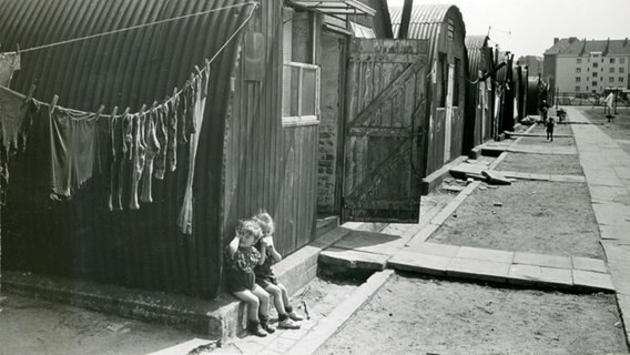 Kinder sitzen vor sogenannten Nissenhütten © NH Foto: NH