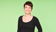 Ein Frau steht vor einem grünen Hintergrund und lächelt in die Kamera © Oliver Fantitsch - Ohnsorg-Theater Foto: Oliver Fantitsch