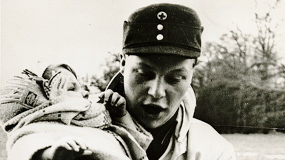 Landunter im Jensch-Park: Klaus-Peter Behrens mit der kleinen Ute Wilhelms im Arm bei der großen Sturmflut 1962. © Deutsches Rotes Kreuz Foto: Deutsches Rotes Kreuz