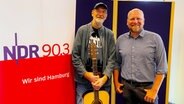 Der Sänger Willie Stemwede aus Hamburg-Rahlstedt und Moderator Jan Wulf stehen in einem Radiostudio vor einem Schild mit dem Aufdruck NDR 90,3. © Verena Böhring - NDR Foto: Verena Böhring - NDR