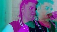 Eine Frau steht vor einer weißen Wand aus Klinkersteinen. © NDR 