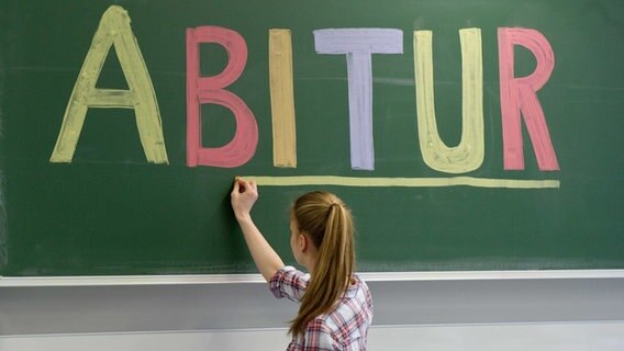 Ein Mädchen schreibt das Wort "Abitur" in bunt an eine Tafel. © picture alliance Foto: Tobias Kleinschmidt