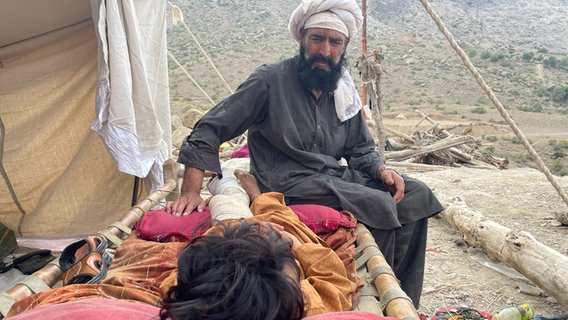 Mann und verletztes Kind sitzen auf einer Trage, Erdbeben in Afghanistan © NDR Foto: Peter Hornung