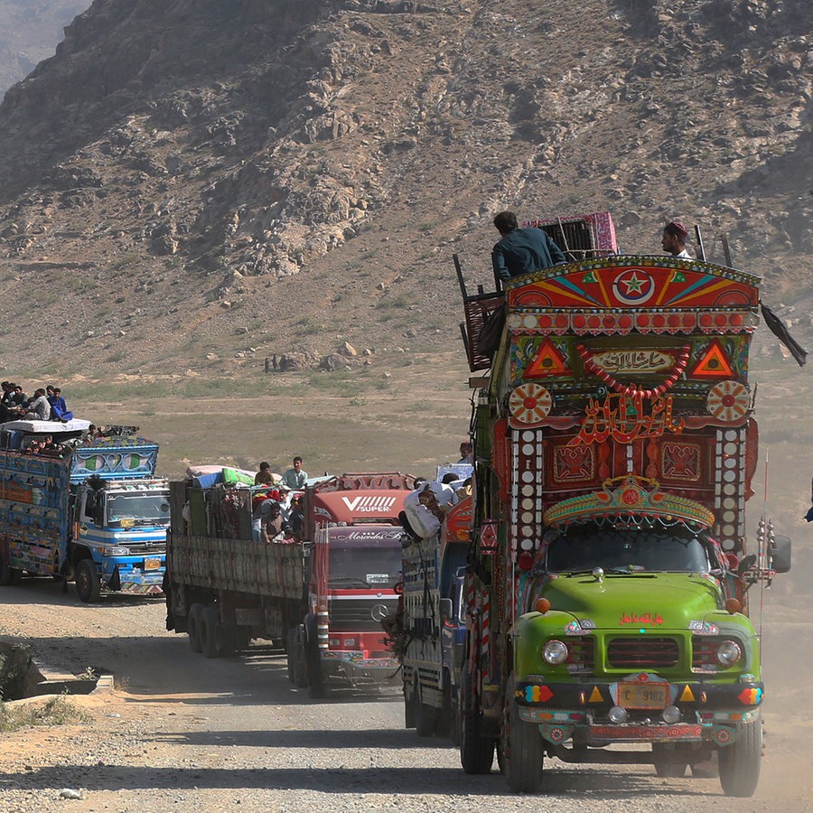 Lastwagen, auf denen afghanischen Familien sitzen, fahren zu einem Grenzübergang. Mit Beginn der geplanten Massenabschiebungen von Flüchtlingen in Pakistan drängen sich Tausende von Menschen an die Grenze zu Afghanistan. Die pakistanische Regierung hatte kürzlich angekündigt, Flüchtlinge ohne Aufenthaltsstatus ausweisen zu wollen. © picture alliance/dpa/AP | Muhammad Sajjad Foto: Muhammad Sajjad