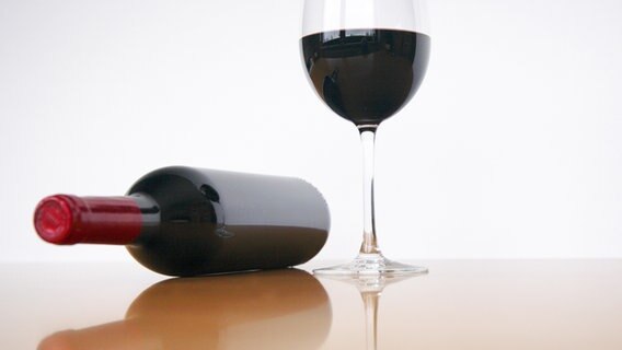 Eine Flasche Wein liegt neben einem gefüllten Rotweinglas. © photocase Foto: markusspiske