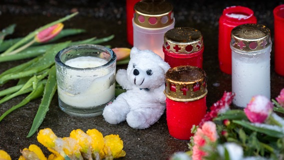 Blumen, Kerzen und ein Teddybär liegen und stehen im Stadtteil Alsterdorf vor dem Eingang zu einer Kirche der Zeugen Jehovas. © dpa Foto: Daniel Bockwoldt