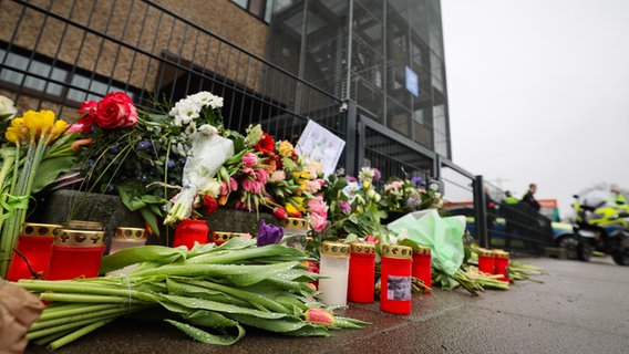 Blumen und Kerzen liegen und stehen im Stadtteil Alsterdorf vor dem Eingang zu einer Kirche der Zeugen Jehovas. © dpa Foto: Christian Charisius