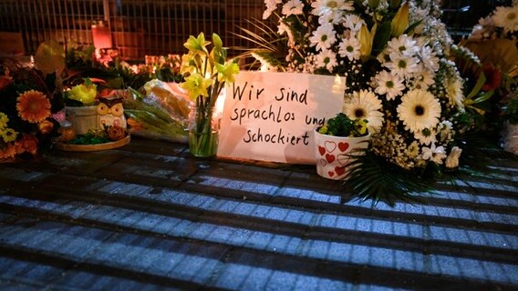 Blumen und Kerzen liegen und stehen im Stadtteil Alsterdorf vor dem Eingang zu einer Kirche der Zeugen Jehovas. © dpa Foto: Jonas Walzberg