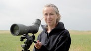 Anne Evers steht mit einem Fernglas im Grünen. ©  Anne Evers 