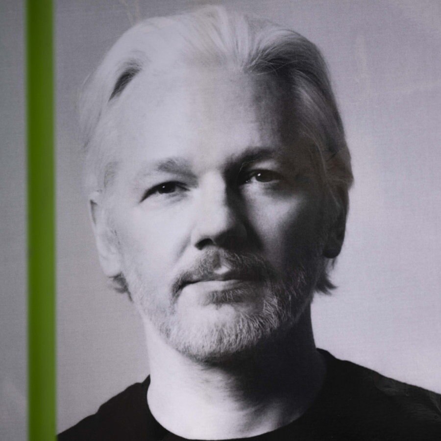 Ein Demo-Plakat vor grünem Hintergrund, das ein schwarz-weiß Porträt von Wikileaks-Gründer Julian Assange zeigt. © picture alliance / AA Foto: Rasid Necati Aslim