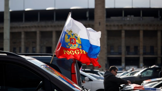 Flaggen mit den russischen Nationalfarben und dem russischen Staatswappen wehen an einem Auto. © picture alliance/dpa/Carsten Koall Foto: Carsten Koall