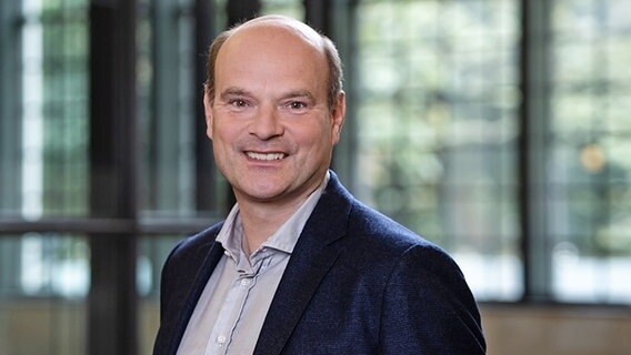 Ein lächelnder Mann mittleren Alters vor einem Fenster: Axel Schneider, Theaterleiter des Hamburger Altonaer Theaters, des Harburger Theaters und der Hamburger Kammerspiele  Foto: Lahola