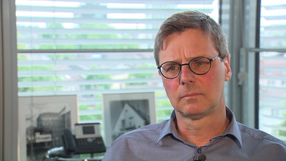 "Spiegel"-Journalist Matthias Bartsch gibt ZAPP in seinem Büro ein Interview. Er hat kurze, graue Haare, trägt eine Brille und ein graues Hemd. © NDR Foto: Screenshot