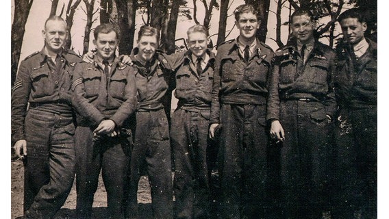 Sieben Soldaten stehen in einer Reihe vor einem Wald © Douglas Wood 