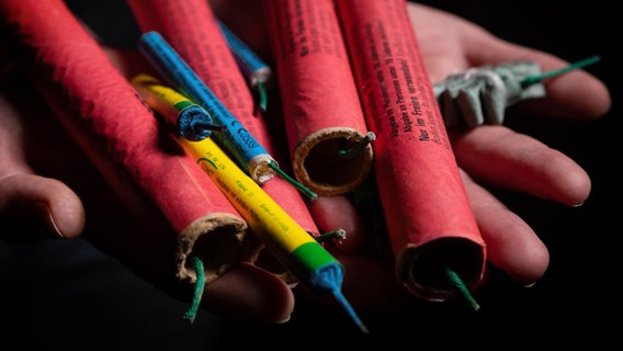 Verschiedene Feuerwerkskörper werden von zwei Händen gehalten. © picture alliance/Andreas Franke 