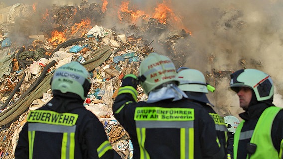 Feuerwehrmänner in Uniform vor einem brennendem Müllhaufen. © dpa - Bildfunk Foto: Susan Ebel